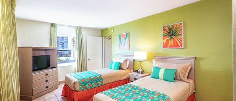 Une chambre d’hôtel avec deux lits, une télévision, un bureau et une fenêtre avec des rideaux.