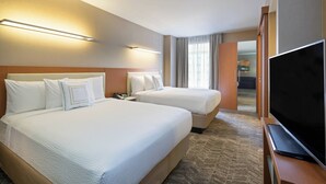 Une chambre d’hôtel avec deux lits, une télévision et un bureau.