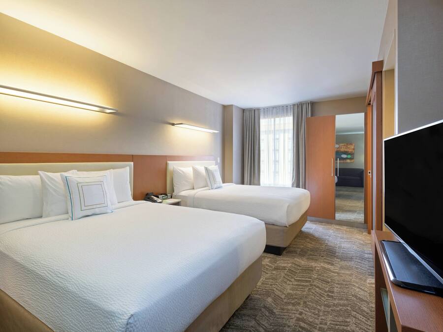 Habitación de hotel con dos camas, un televisor y un escritorio.