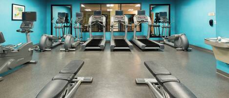 A gym with treadmills, elliptical machines, and weight benches.