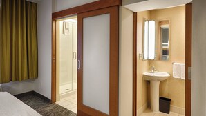 A hotel room with a bed, a shower, a sink, and a mirror. - SpringHill Suites by Marriott Albany-Colonie (Albany)