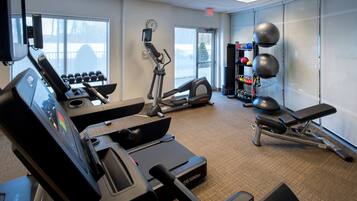Ett gym med konditionsmaskiner, hantlar och träningsbollar.