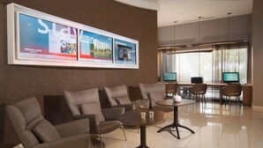 Un moderno vestíbulo de hotel con una zona de estar, una recepción y una gran pantalla digital.