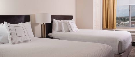 Two twin beds with white linens and a nightstand with a lamp.