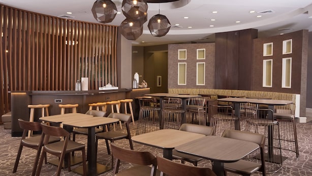 Un restaurante moderno con mobiliario de madera, una zona de bar y una alfombra estampada.