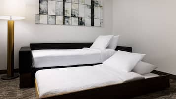 A modern hotel room with a large bed, a bedside table, a lamp, and a wall art piece.