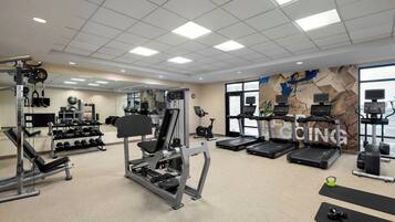 A gym with various exercise equipment, including treadmills, weight machines, and dumbbells.