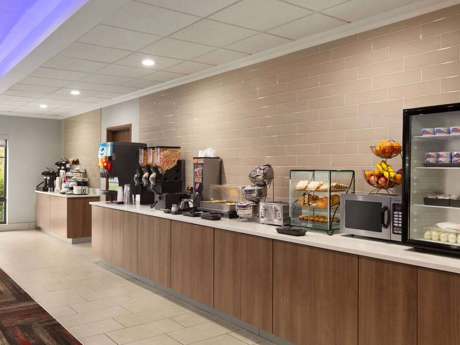 A hotel reception area with a counter, coffee machines, a microwave, and a refrigerator stocked with food.