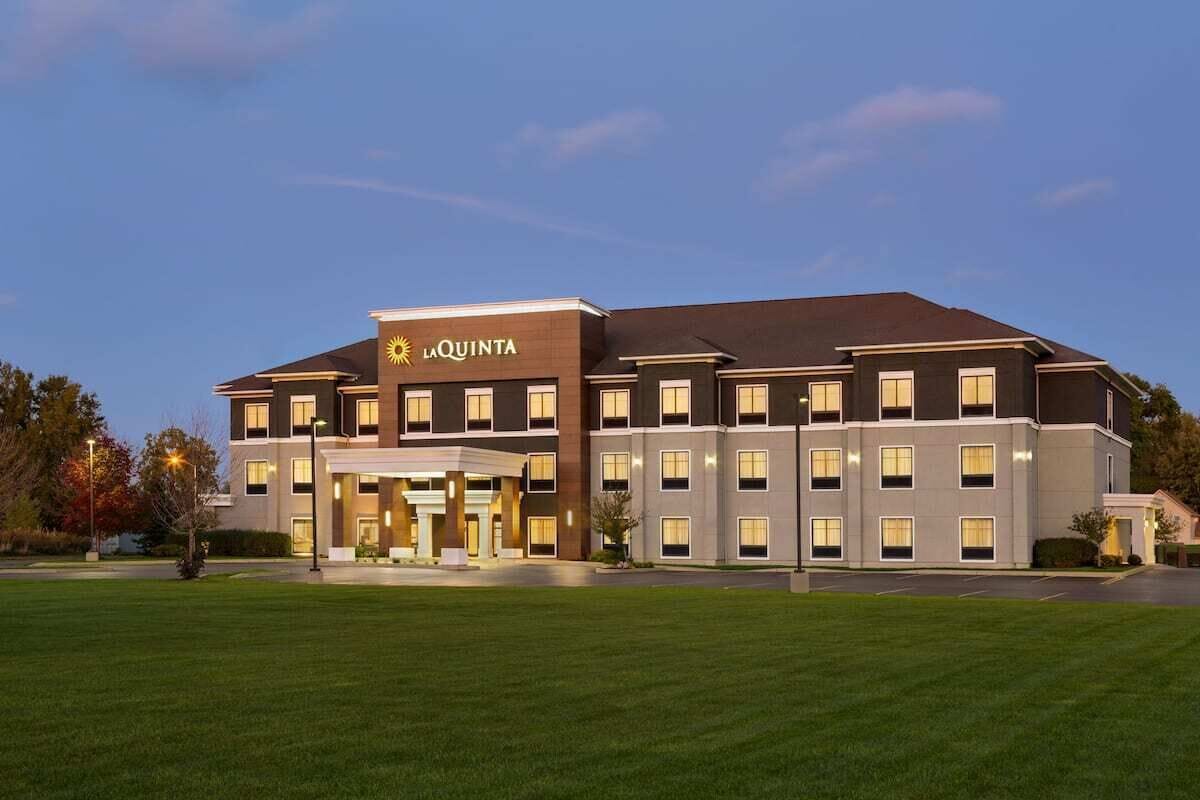 A multi-story hotel with a prominent 'La Quinta' sign, featuring a modern architectural design with a flat roof and symmetrical windows.