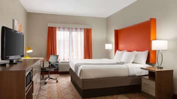 Een hotelkamer met een bed, bureau, televisie en twee bedlampen.