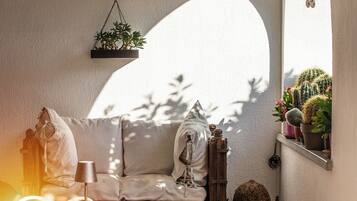 A cozy patio with a white sofa, a table, chairs, and potted plants.
