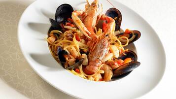 Un plat de pâtes aux fruits de mer servi dans une assiette blanche.