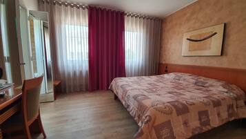 Een hotelkamer met een bed, een bureau, een stoel en een raam met gordijnen.