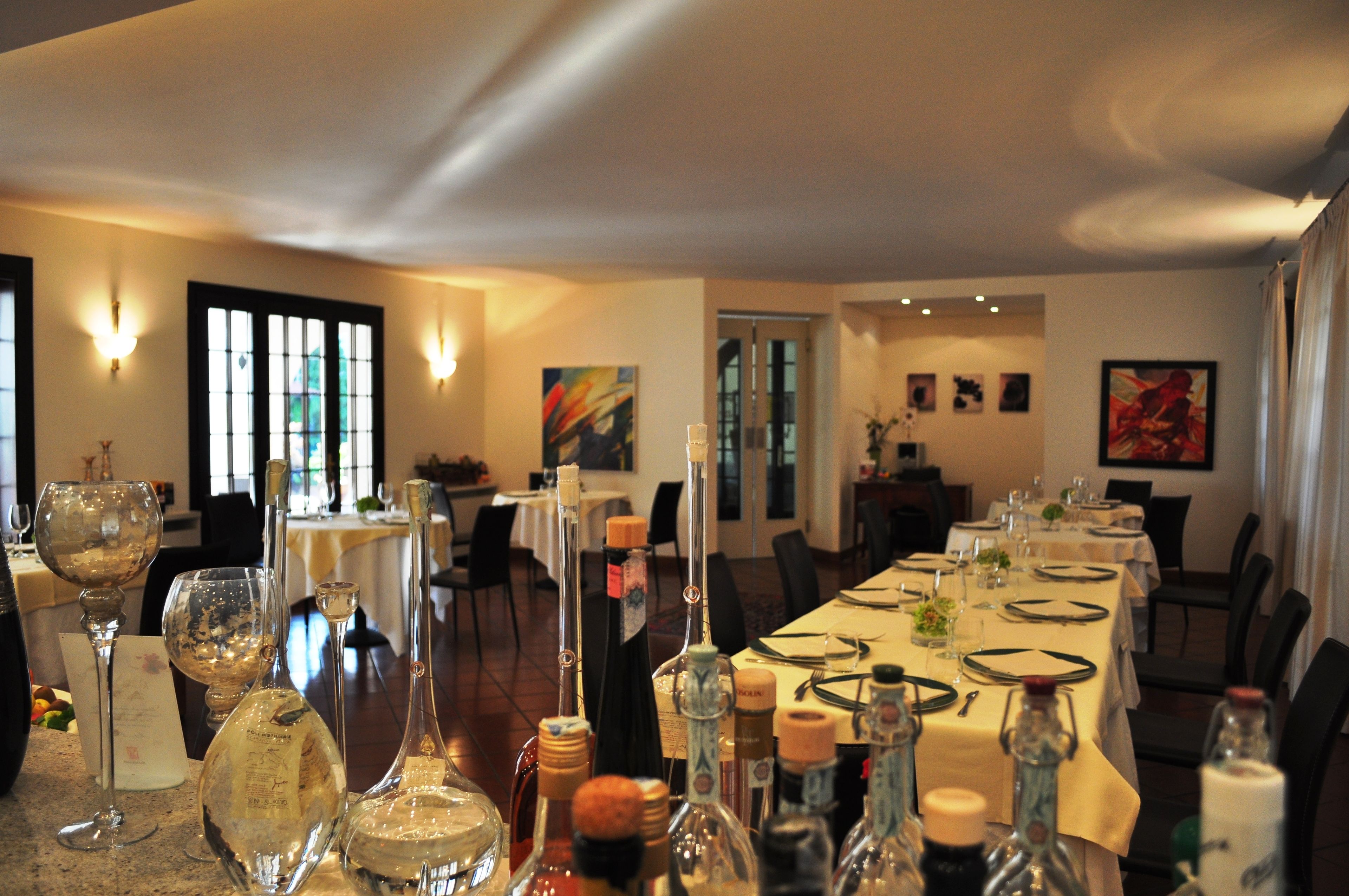 A dining area with tables set for a meal, wine glasses, and bottles.