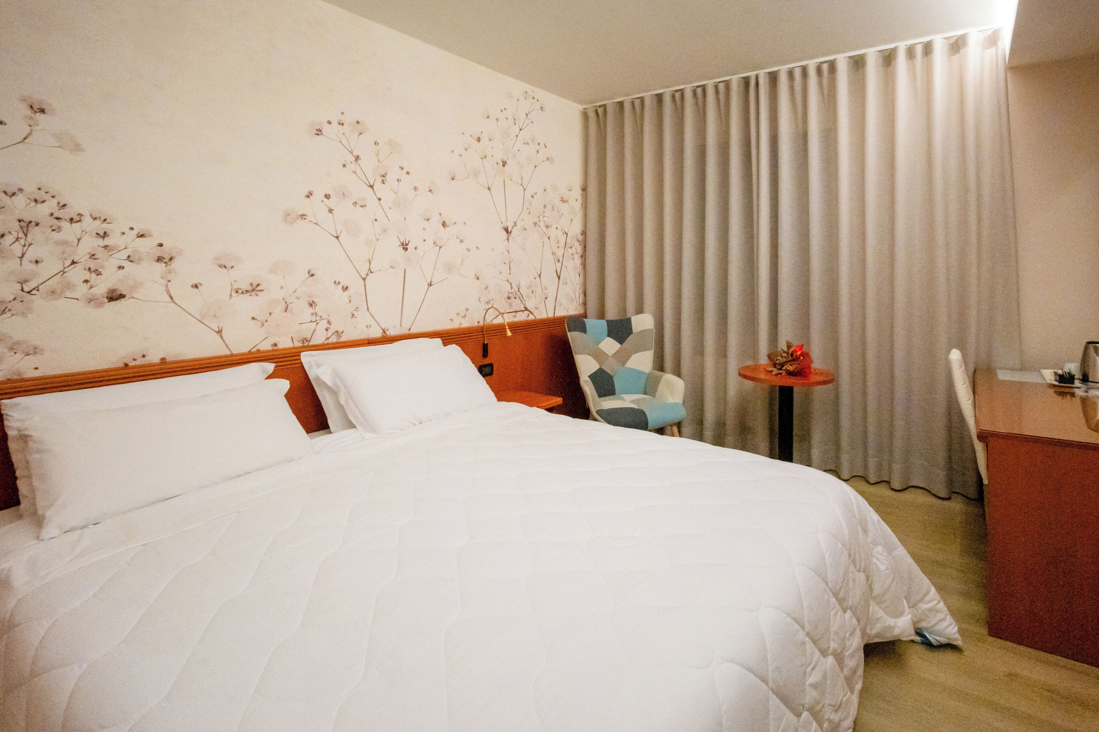 Une chambre d’hôtel avec un grand lit, un bureau, une chaise et une petite table.