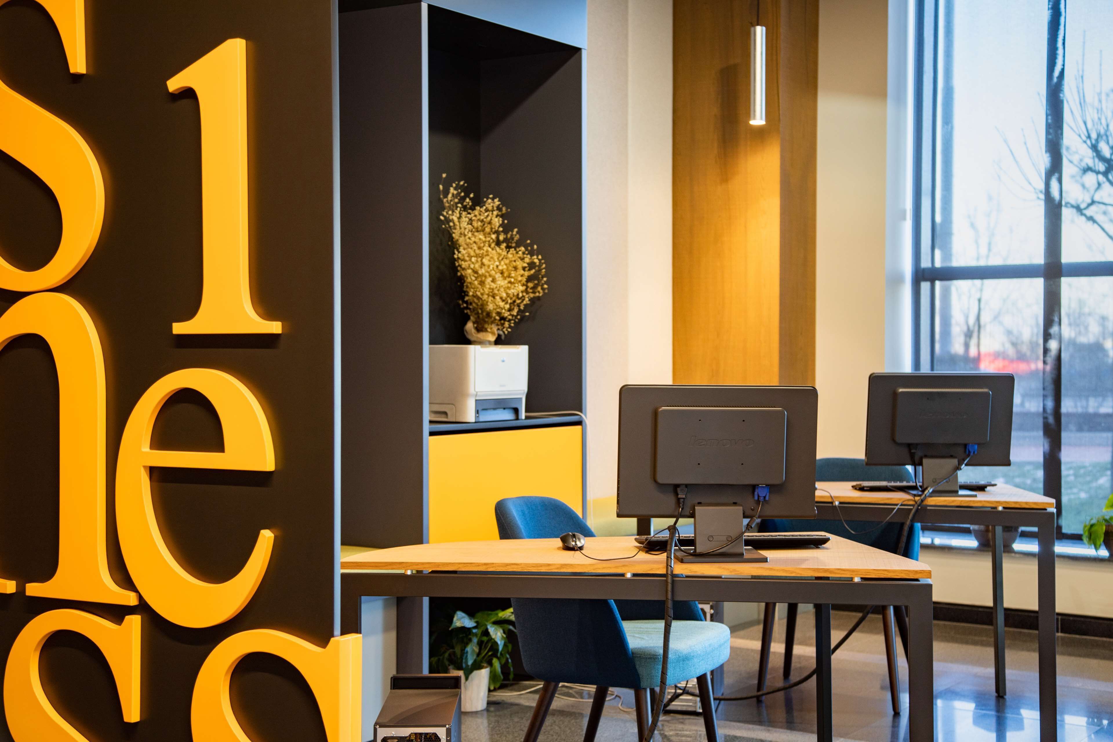 A modern office space with cubicles, computers, and a large window.