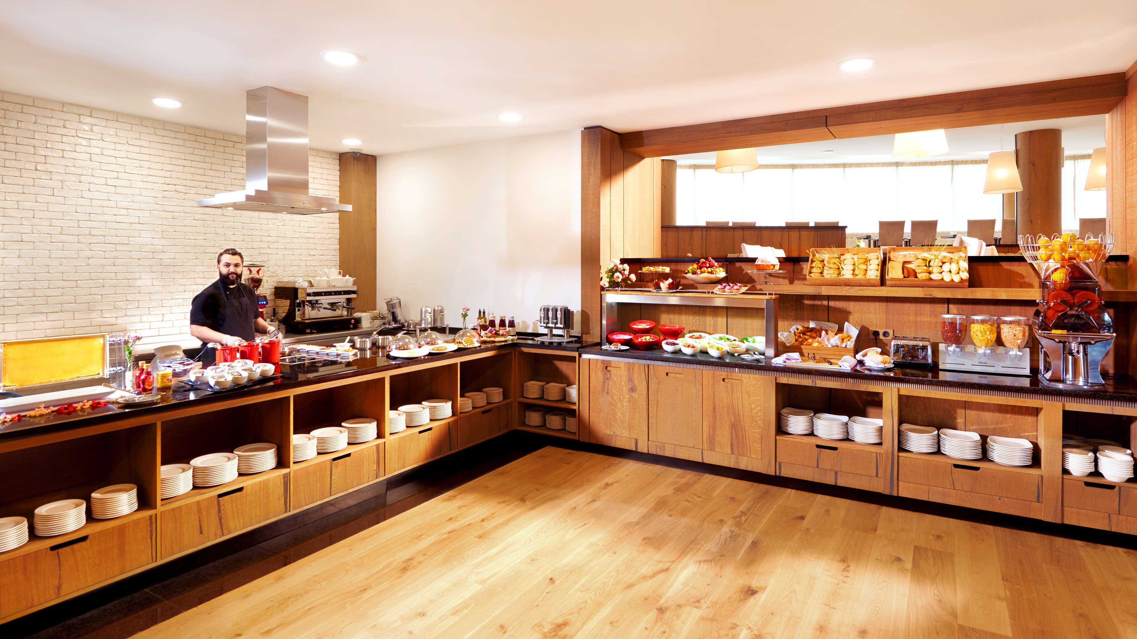 Un bufé de desayuno moderno con diversas opciones de comida, una estación de café y un barista preparando bebidas.