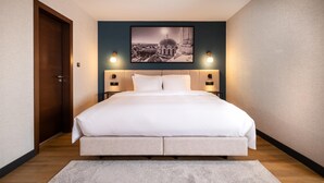 A modern hotel room with a large bed, a framed cityscape picture on the wall, and two bedside lamps. - Metropolitan Hotel Sofia, a member of Radisson Individuals (Sofia)