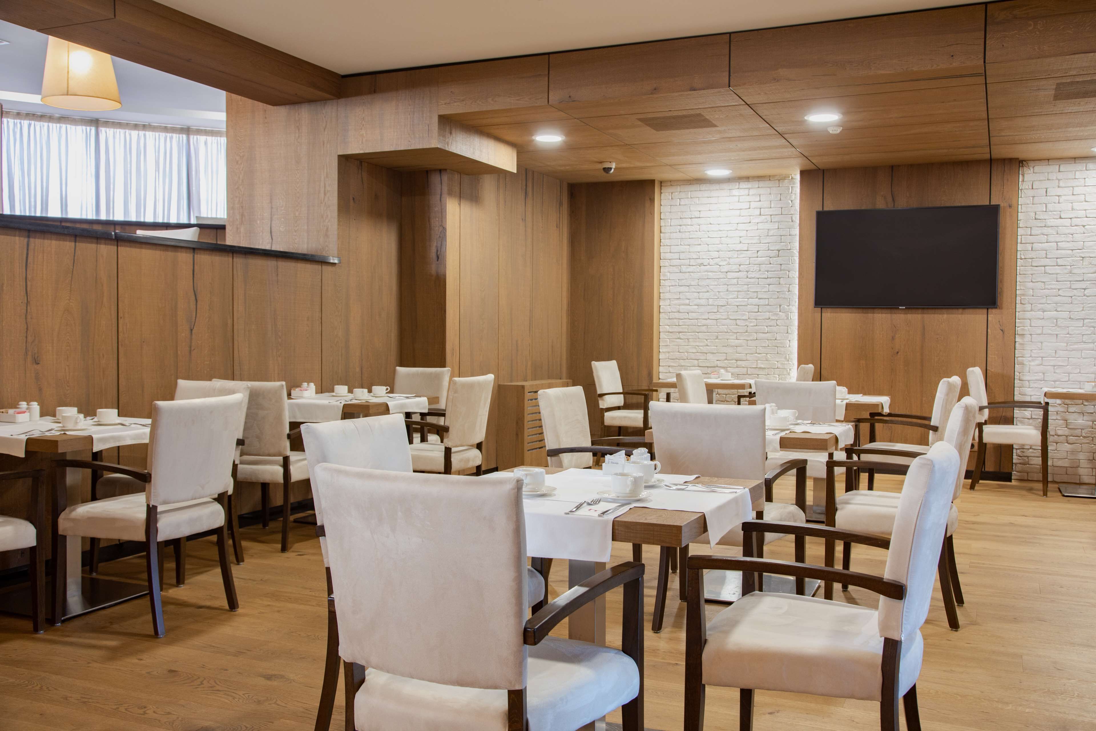 Un salón de conferencias con paneles de madera, mesas y sillas blancas.