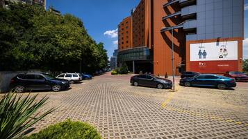 A parking area with cars, a building with a billboard, and trees.
