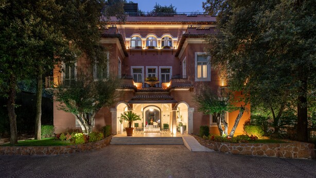 A large, two-story building with a central entrance, surrounded by trees and a cobblestone driveway. - Hotel Principe Torlonia (Rome)