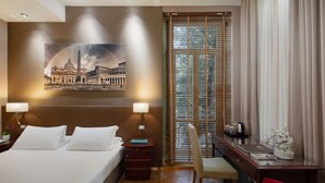 A hotel room with a large bed, two bedside lamps, a desk with a chair, a coffee maker, and a framed picture on the wall. - Hotel Principe Torlonia (Rome)