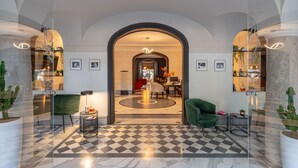 A spacious lobby with a checkered floor, a green armchair, and a modern chandelier. - Hotel Principe Torlonia (Rome)