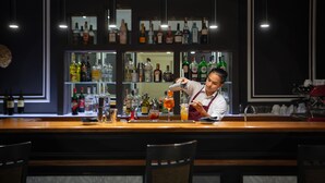 A bar area with a bartender preparing drinks, shelves with various bottles, and a coffee machine. - Hotel Principe Torlonia (Rome)