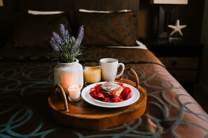 A wooden tray with a plate of strawberries and a pastry, a candle, and a vase with lavender on a bed. - The Beach Club at Anna Maria by RVA (Bradenton Beach)
