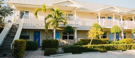 Et fleretagers hotel med flad tag, overdækket veranda og en trappe til indgangen.