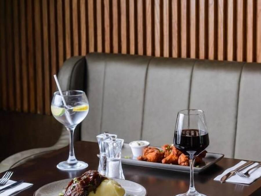 Un restaurante con pared de madera, una mesa con un plato de comida y dos copas de vino.