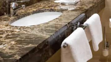 Ein Badezimmer mit Marmor, einem Waschbecken, zwei Handtuchhaltern und einem Spiegel.