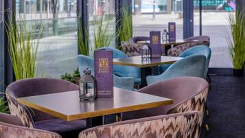 A restaurant interior with seating arrangements, tables, and a menu stand.
