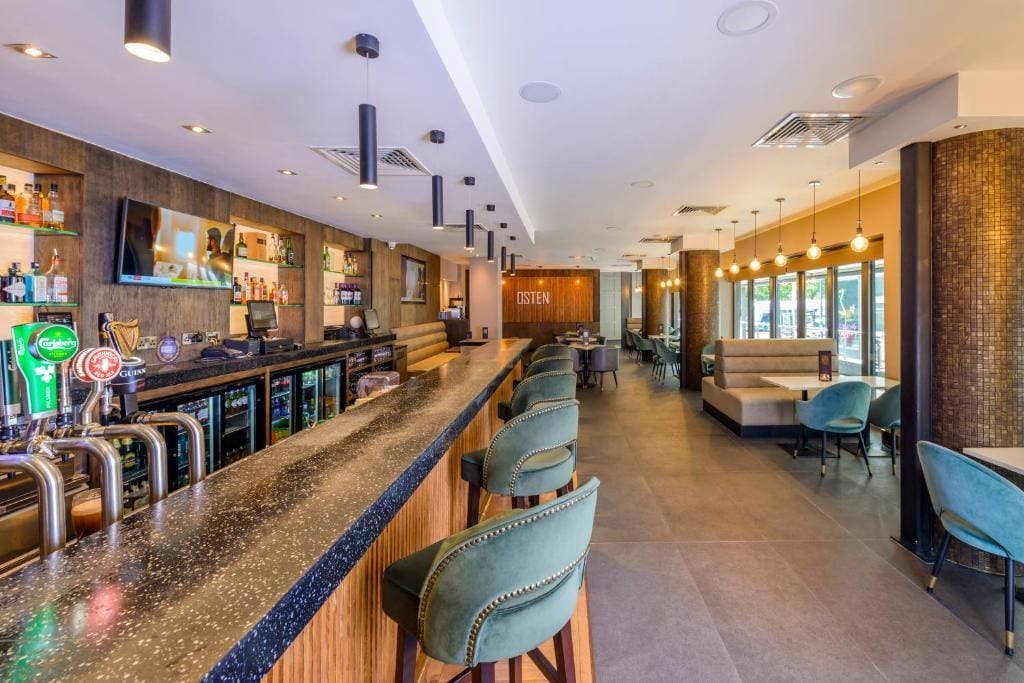 A bar area with a long counter, multiple taps, and seating arrangements.
