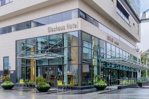 Um hotel moderno com fachada de vidro, área de estar externa e vista clara do interior.