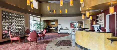A hotel lobby with a reception desk, seating area, and a large mirror wall.
