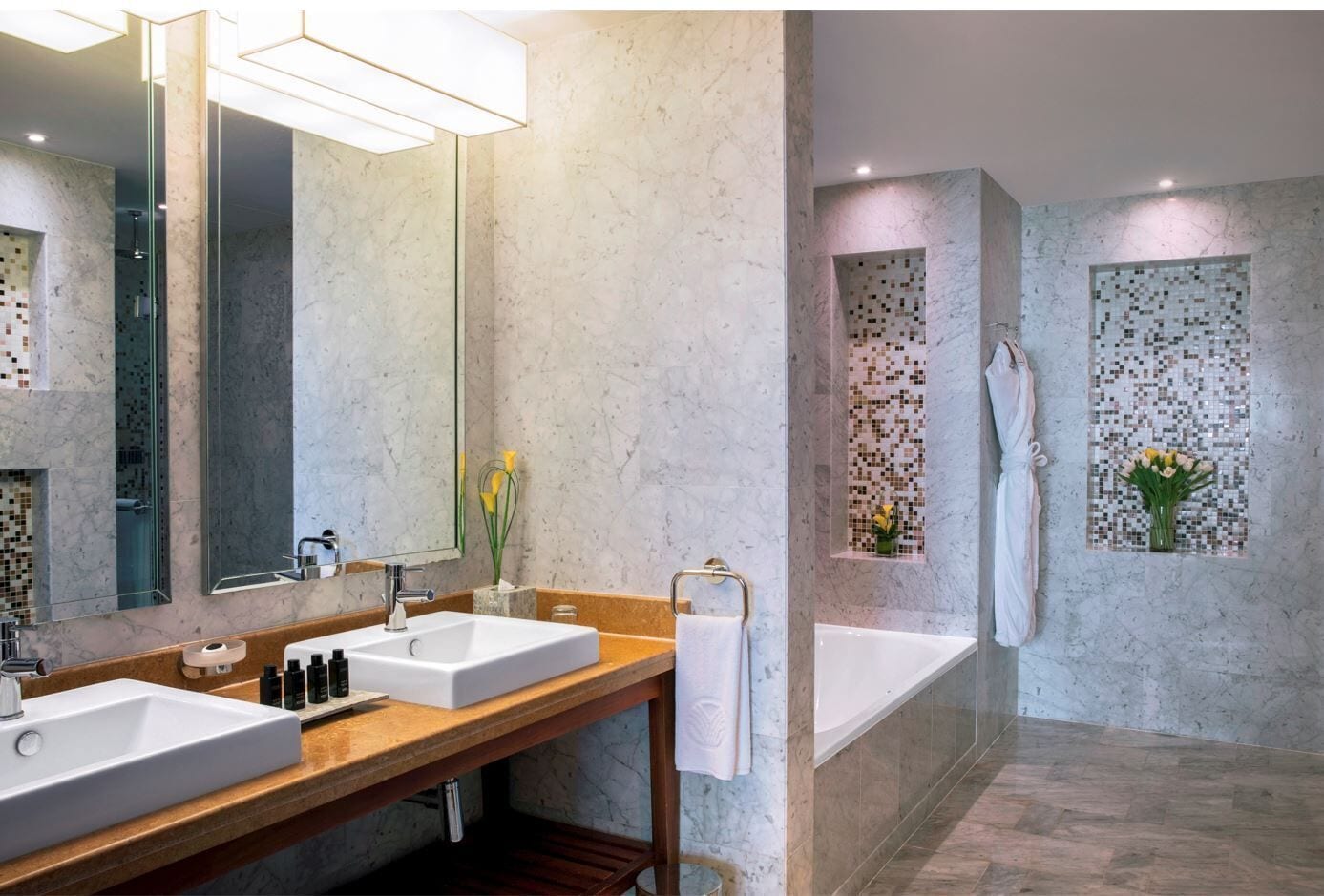 Une salle de bain moderne avec deux lavabos, un grand miroir et une baignoire.