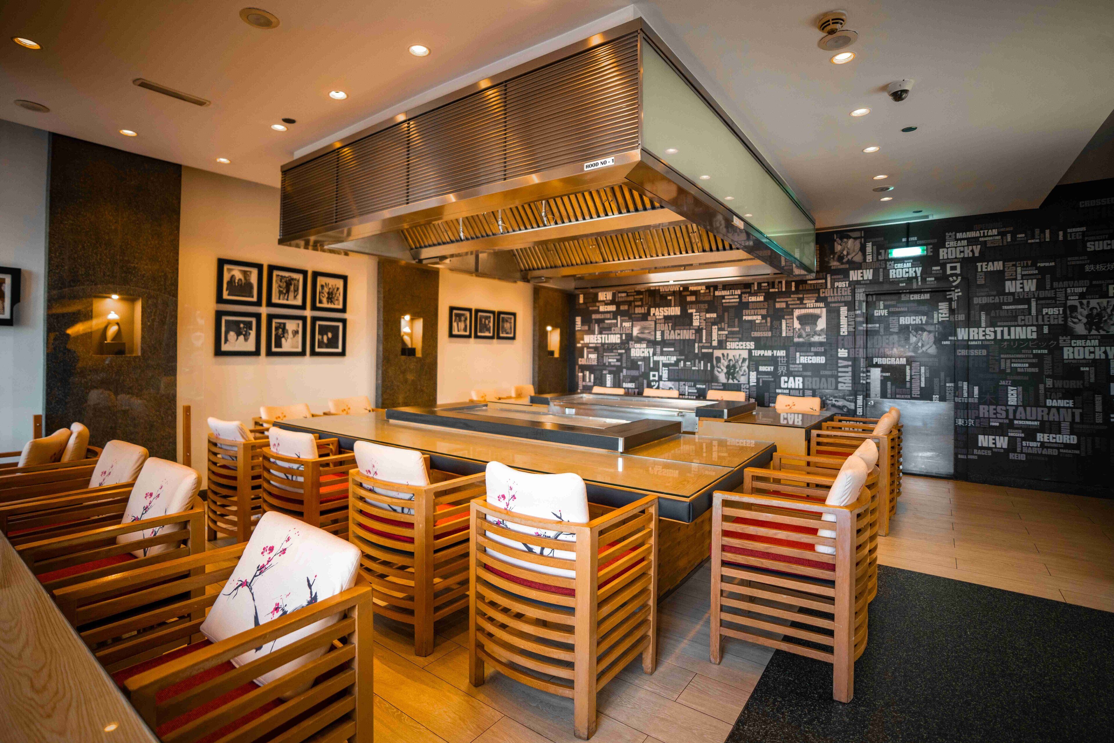 Un restaurante con sillas de madera y una mesa central, rodeado de cuadros en las paredes.