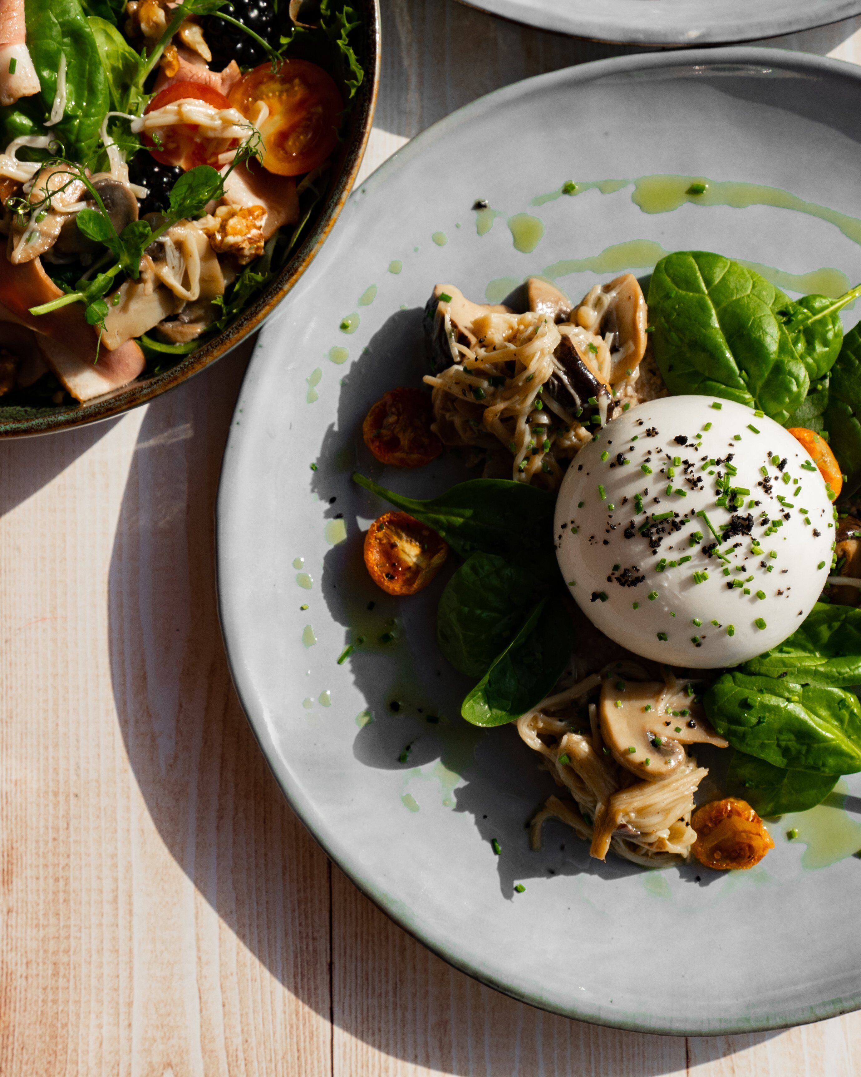 A plate of food with a poached egg, mushrooms, and greens.