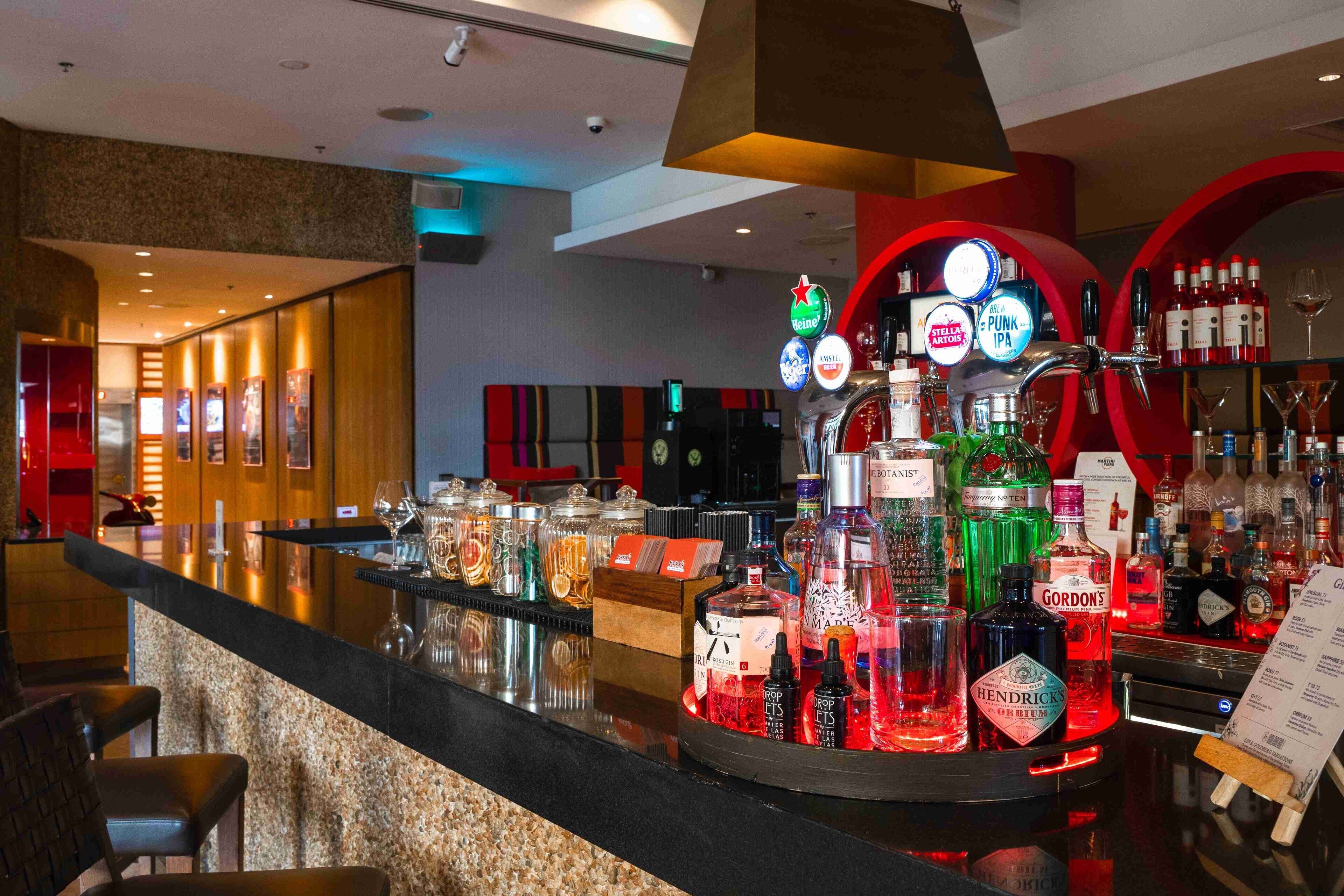 Zona de bar con una variedad de botellas de licor, una grifería de cerveza y un interior bien iluminado.
