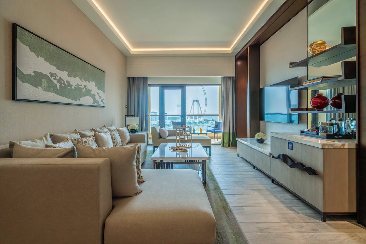A modern hotel room with a living area, a dining table, and a kitchen.
