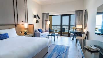 Une chambre d’hôtel avec un grand lit, un bureau, une chaise, une petite table et un balcon donnant sur la ville.