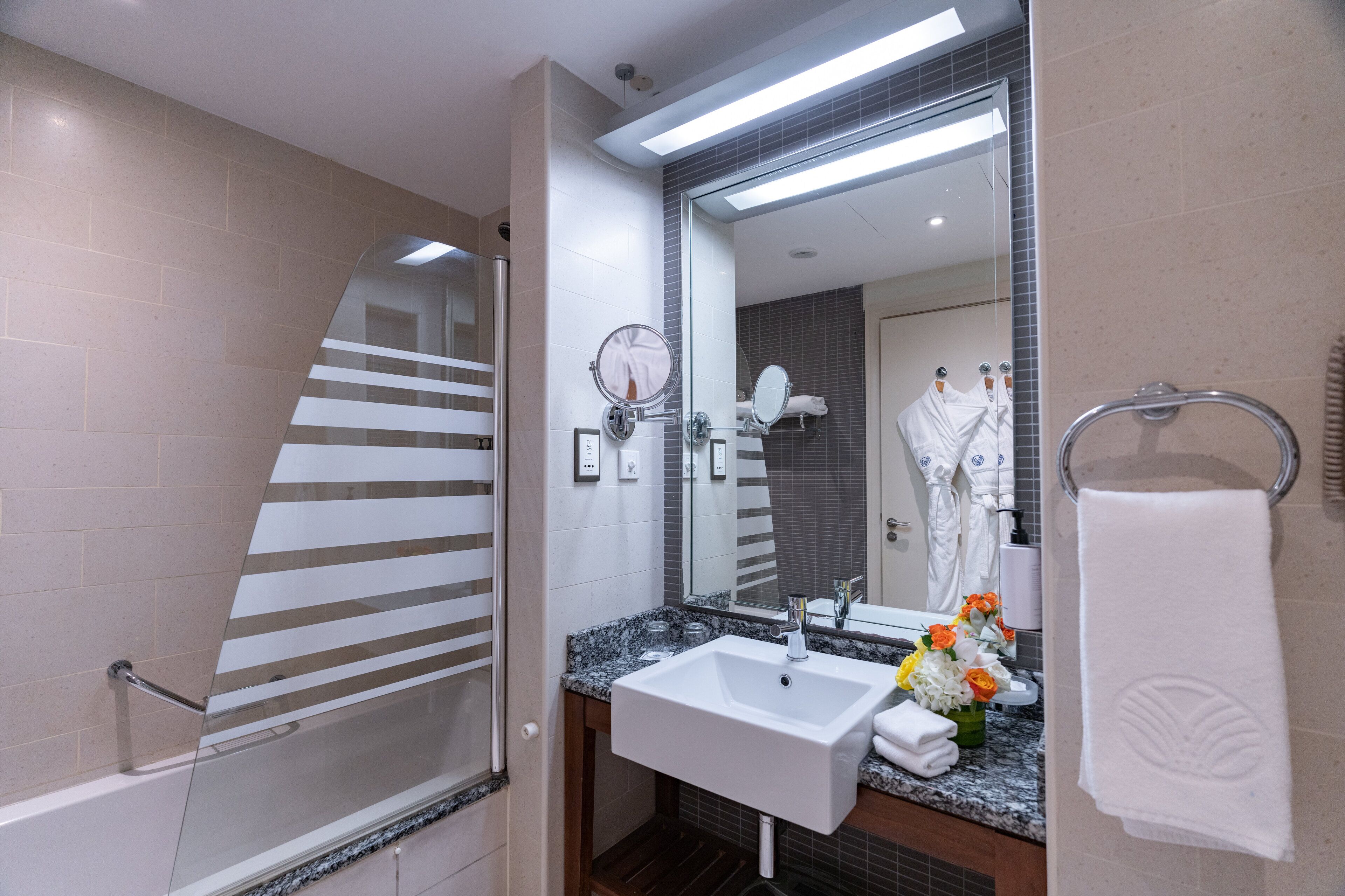 A modern bathroom with a glass shower enclosure, a white sink, and a large mirror.