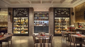 A restaurant with brick walls, a central counter, and tables with striped chairs.