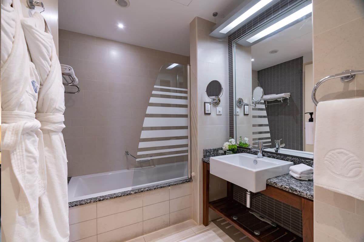 A modern bathroom with a bathtub, a sink, and a large mirror.