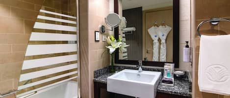 Une salle de bain moderne avec une douche à l’italienne en verre, un lavabo blanc et un grand miroir.