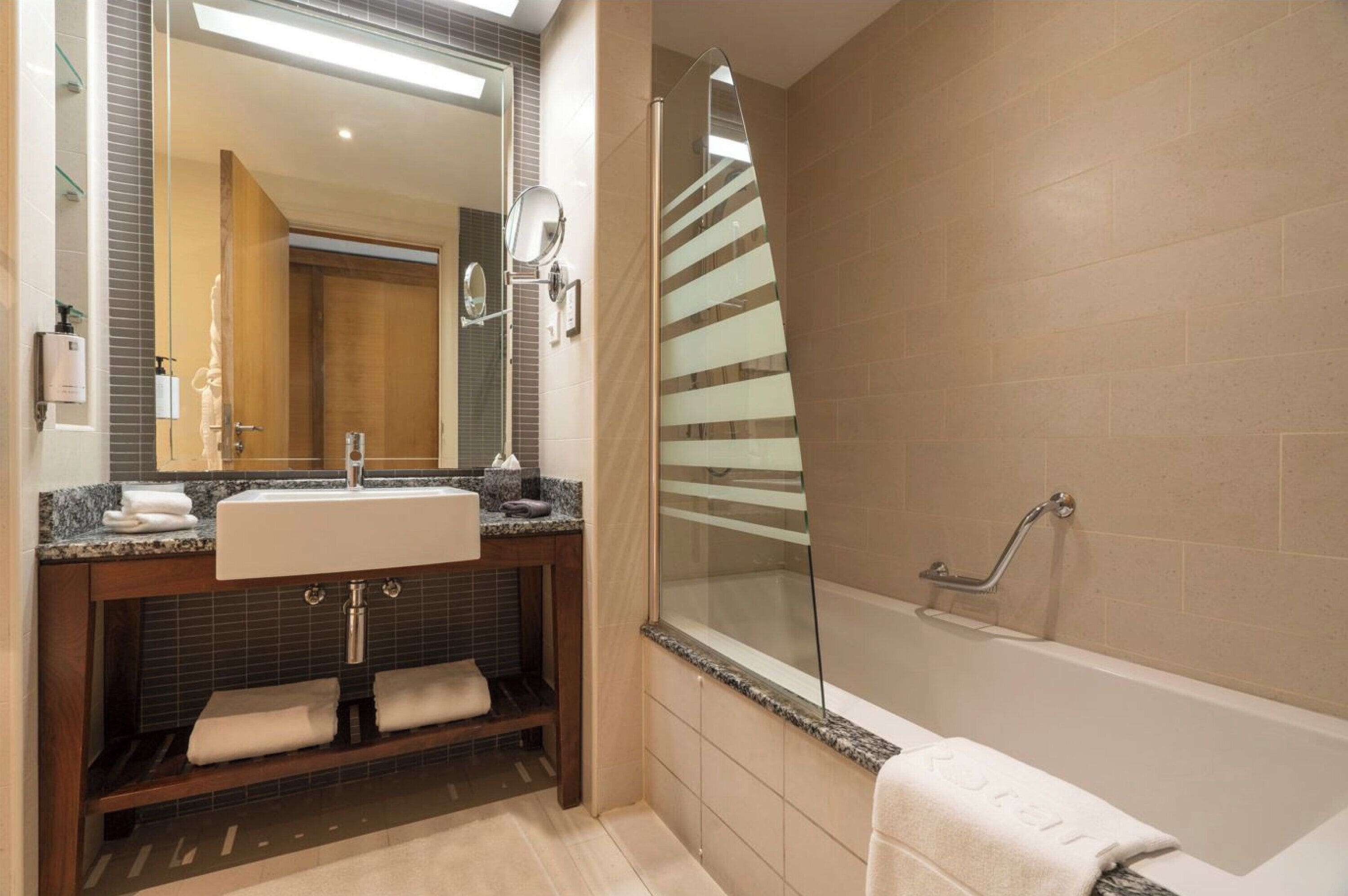 Une salle de bain moderne avec un lavabo, un miroir et une douche à parois de verre.