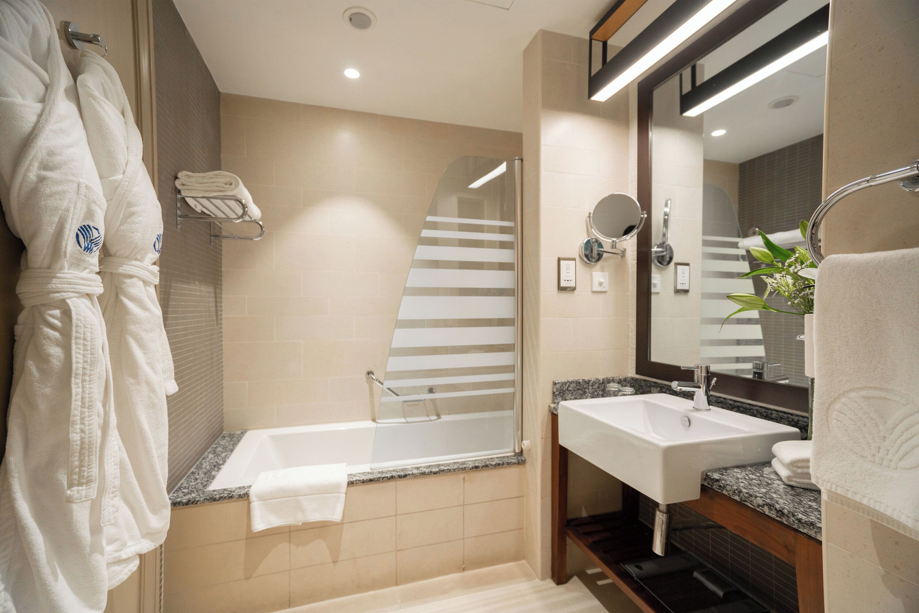 A modern bathroom with a bathtub, a sink, and a mirror.
