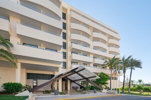 Un hotel de varios pisos con un diseño moderno, con balcones y una entrada cubierta.