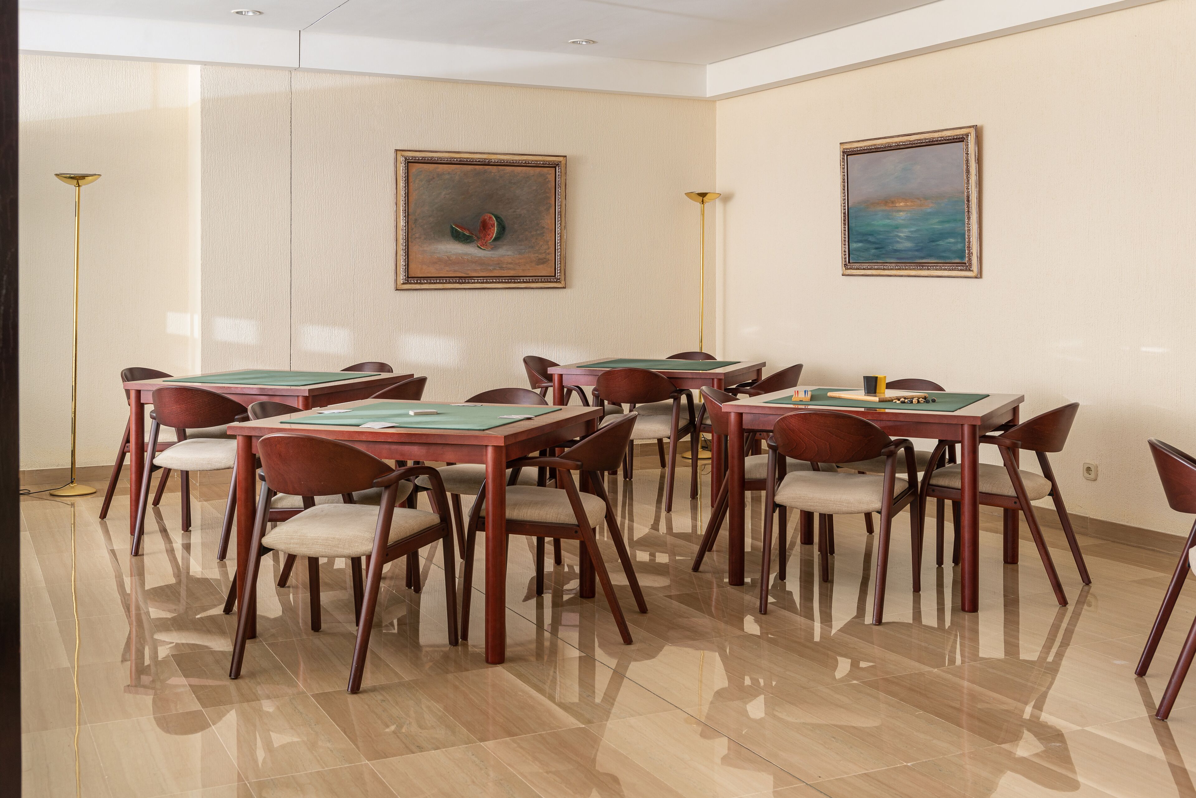 Une salle de conférence dotée de plusieurs tables et chaises, de deux tableaux accrochés aux murs et d’un plancher ciré.